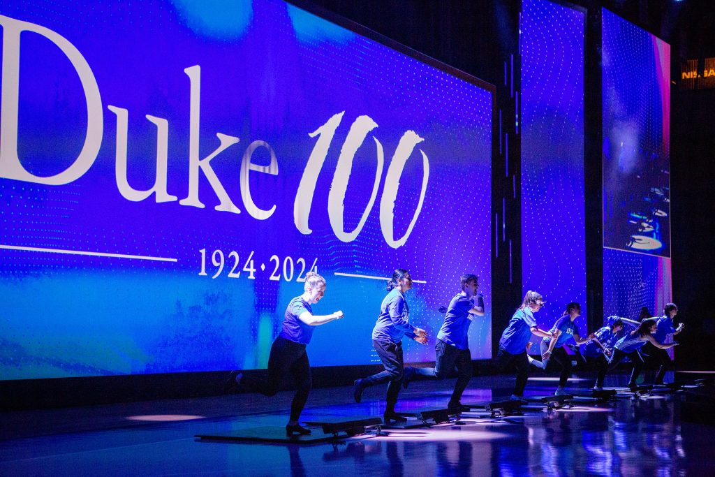 On Tap starts the show tap dancing in front of the Duke100 logo on a large screen