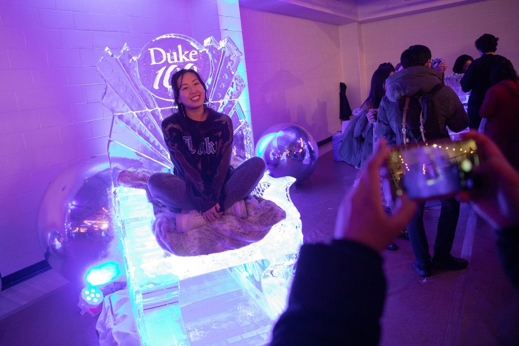 A student sites on a Duke 100 ice sculpture throne
