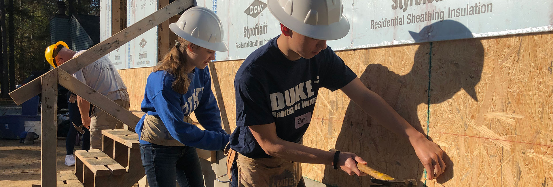 Students hammering on a Habitat for Humanity house
