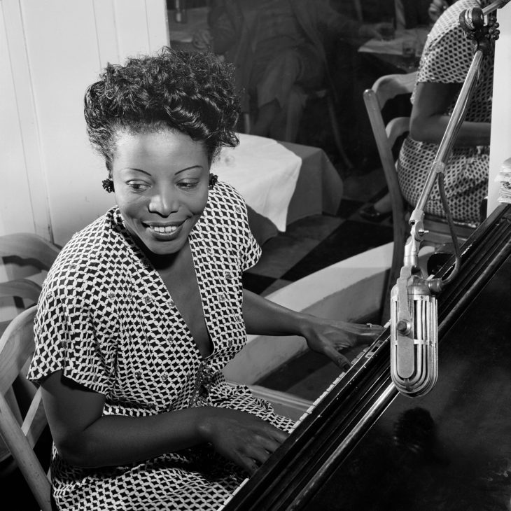 A black and white photo of Mary Lou Williams playing the piano