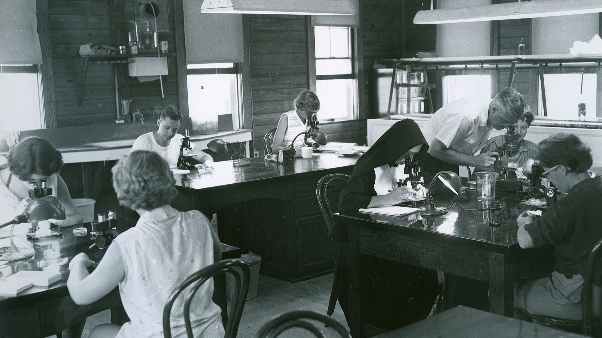 A historical photo of students at lab tables looking through microscopes