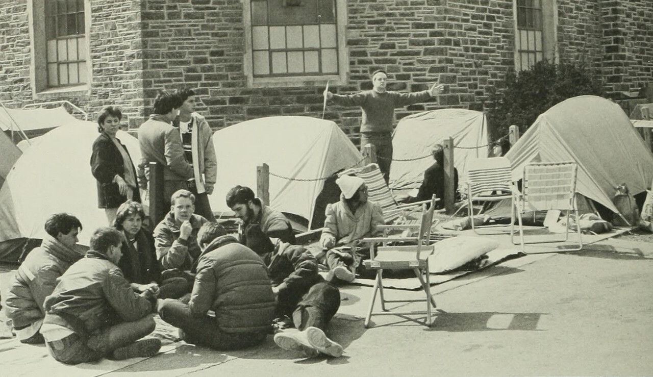 Students sit in a circle next to tents outside Cameron Indoor Stadium