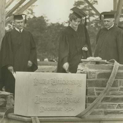 Doris Duke, in cap and gown, sets the cornerstone for West Campus