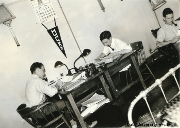 A historic photo of engineering students at Desks with a Duke penant on the wall