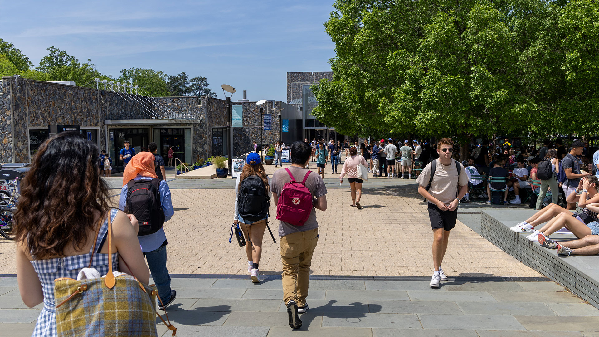 Students enjoying the wide tree-lined plaza in front of the Bryan Center