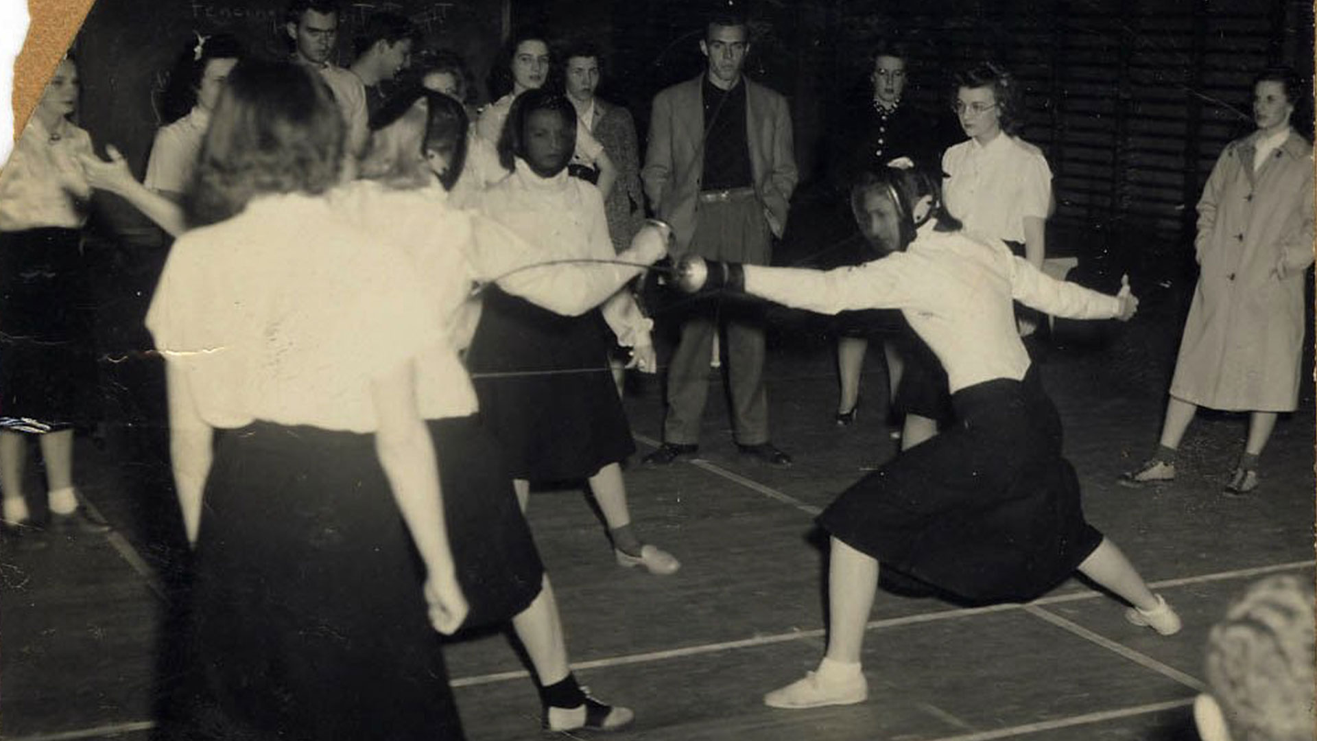 An old torn photo of Duke women fencing in long skirts