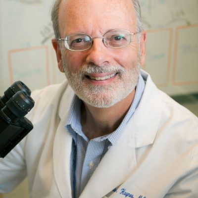 Bart Haynes headshot in a lab coat next to a microscope