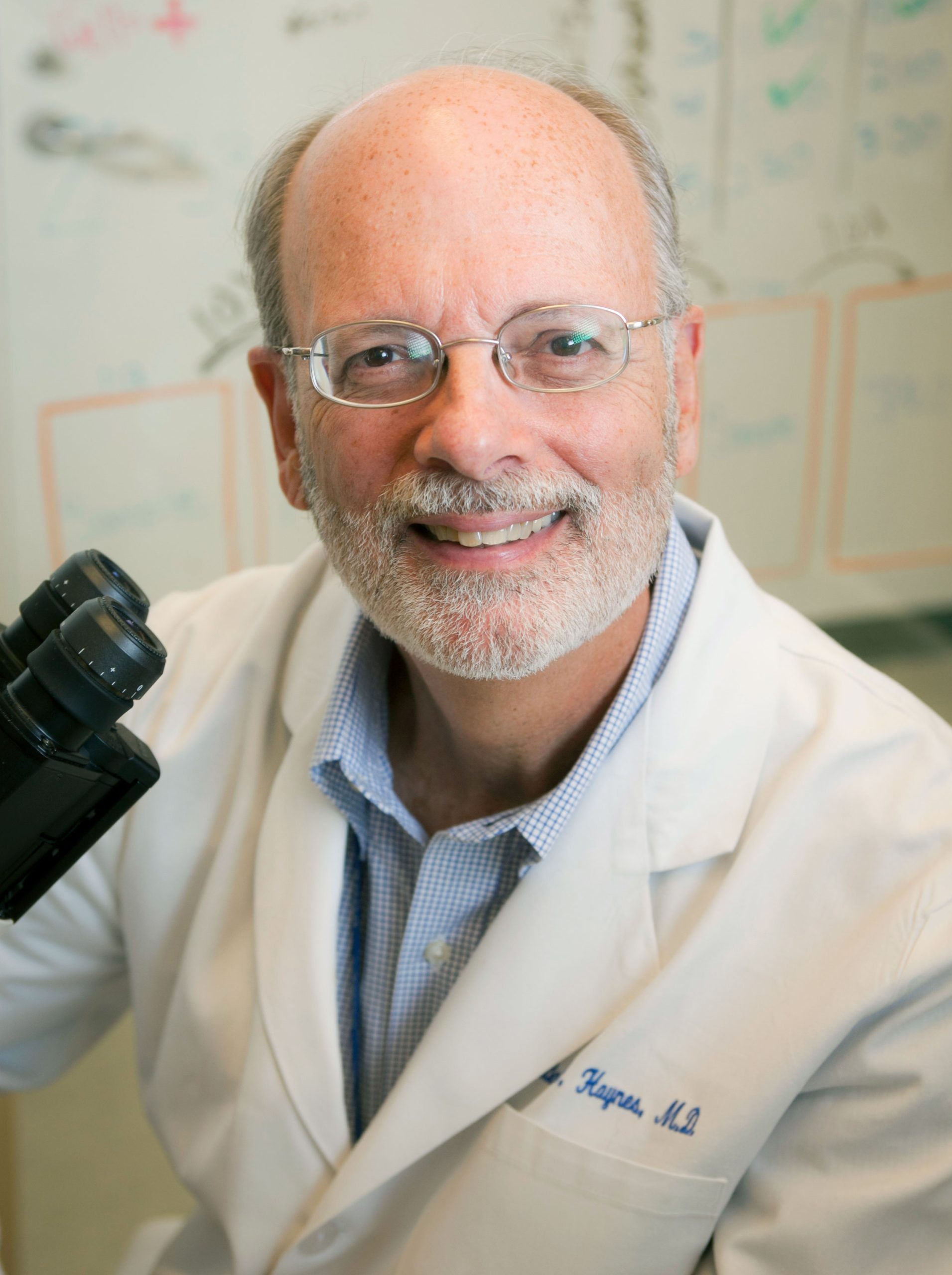 Bart Haynes headshot in a lab coat next to a microscope