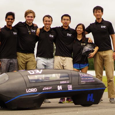 Duke EV team standing around a small aerodynamic vehicle