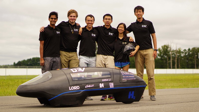 Duke EV team standing around a small aerodynamic vehicle