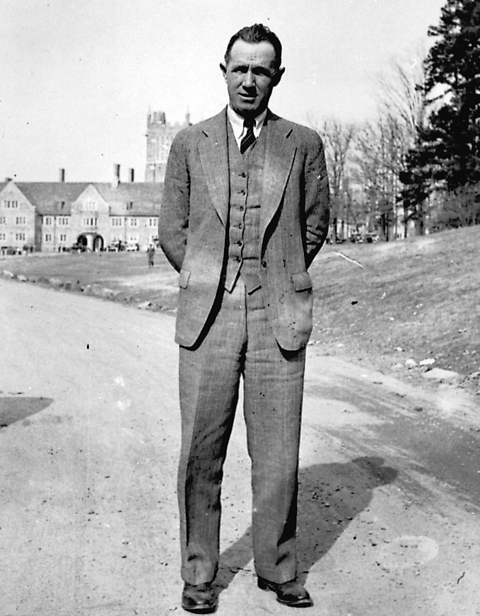 Wallace Wade stands on a dirt road on West Campus with the clocktower in the background