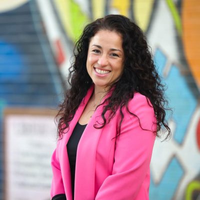 Rosa Gonzalez-Guarda portrait in front of colorful, spray-painted wall