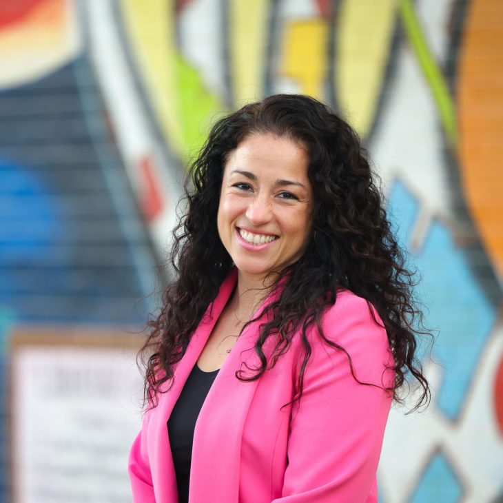 Rosa Gonzalez-Guarda portrait in front of colorful, spray-painted wall