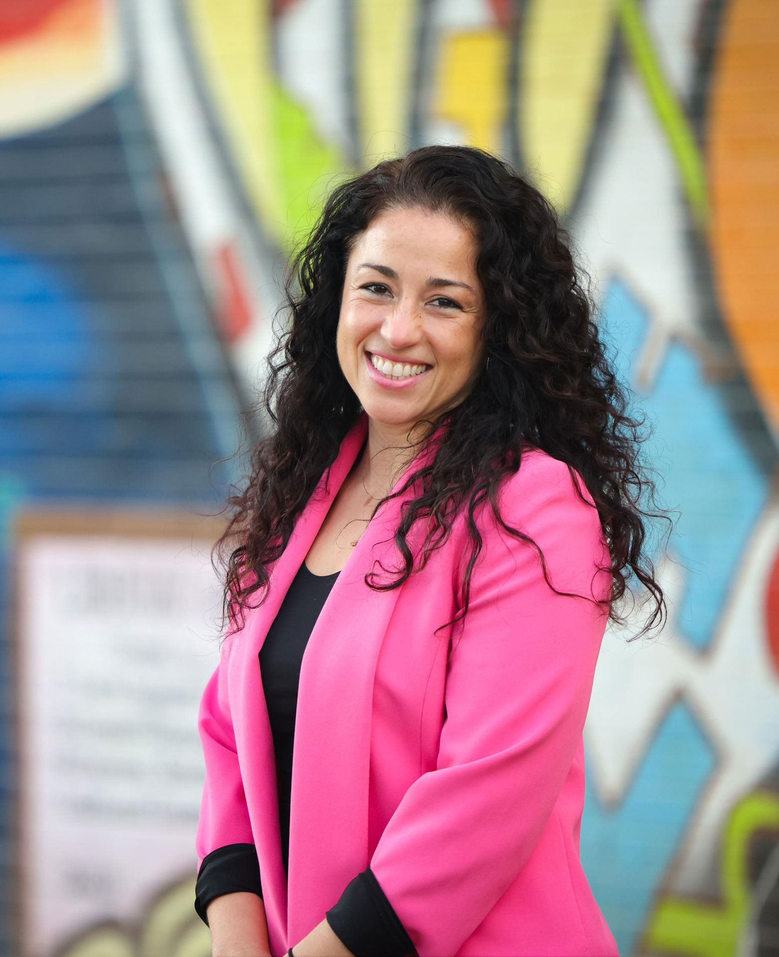 Rosa Gonzalez-Guarda portrait in front of colorful, spray-painted wall