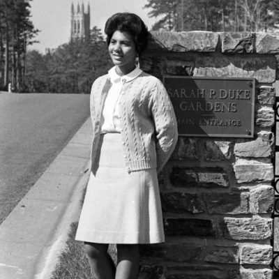 Wilhelmina Reuben-Cooke standing by a Stone wall with Duek Chapel in the background in 1967