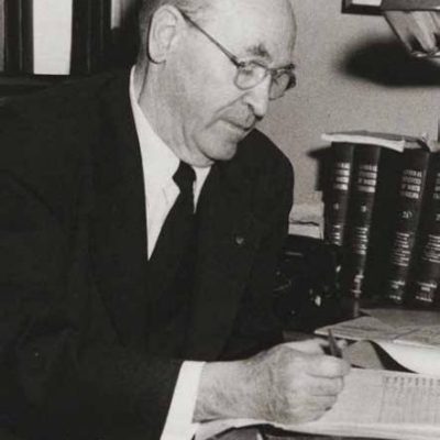 John Bradway writing in a ledger at a desk