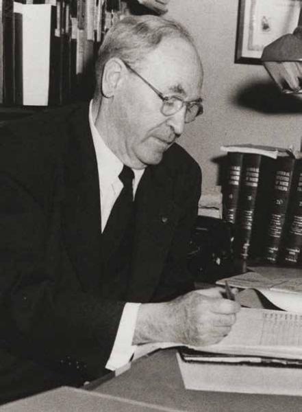 John Bradway writing in a ledger at a desk