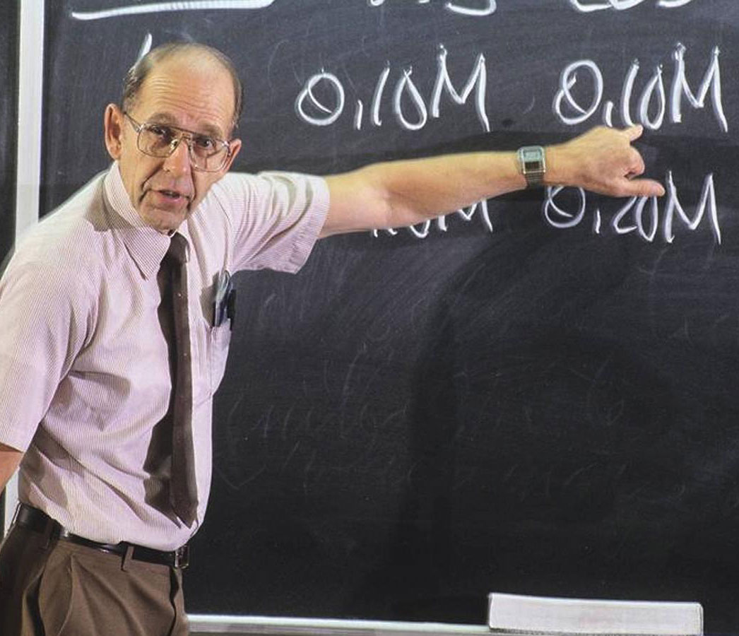 James Bonk pointing to a chalk board